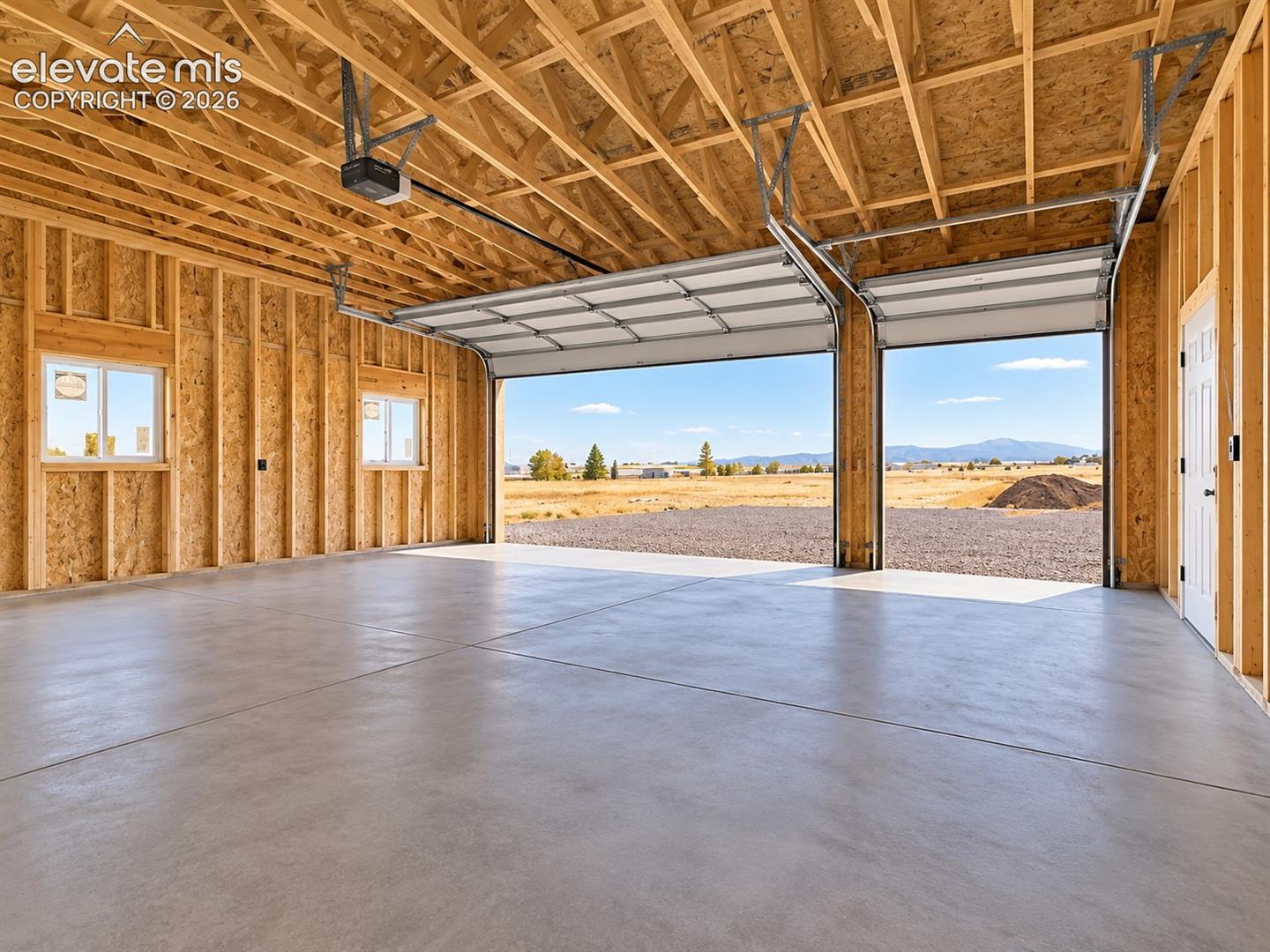 Detached Garage Interior – Spacious detached garage features multiple overhead doors, a finished concrete floor, windows for natural light, and generous room for vehicles, equipment, storage, or workspace.