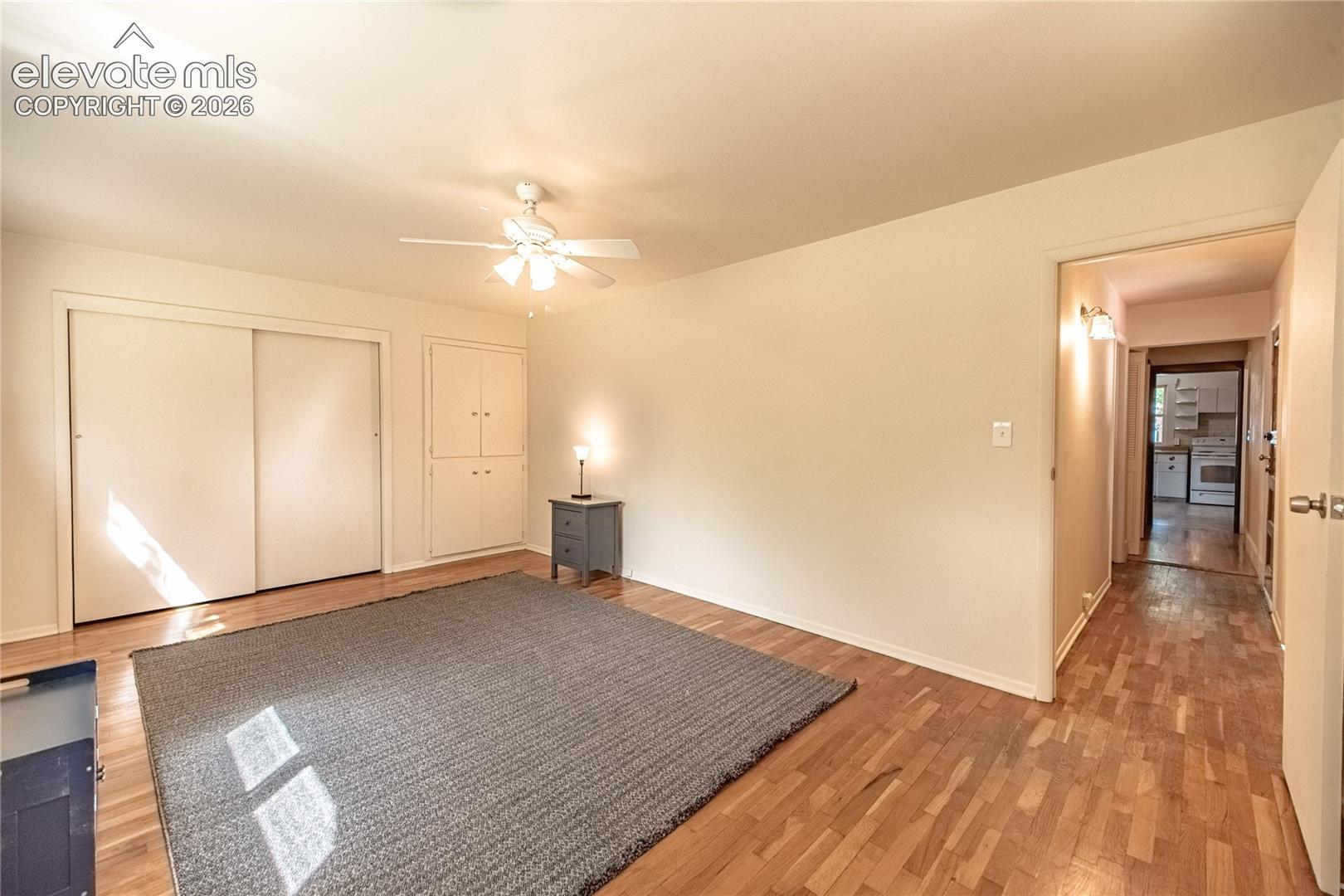 Wood-finish flooring with built-in cabinetry, sliding closet doors, a ceiling fan, and recessed lighting