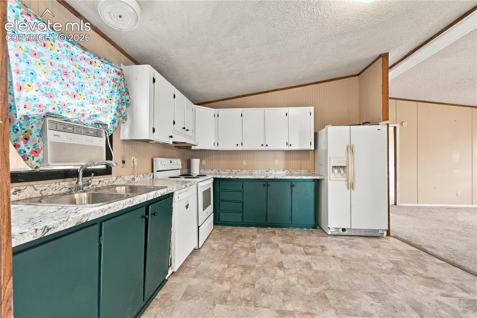 Kitchen featuring white upper cabinetry, teal lower cabinetry, white appliances, a double basin sink, and laminate flooring