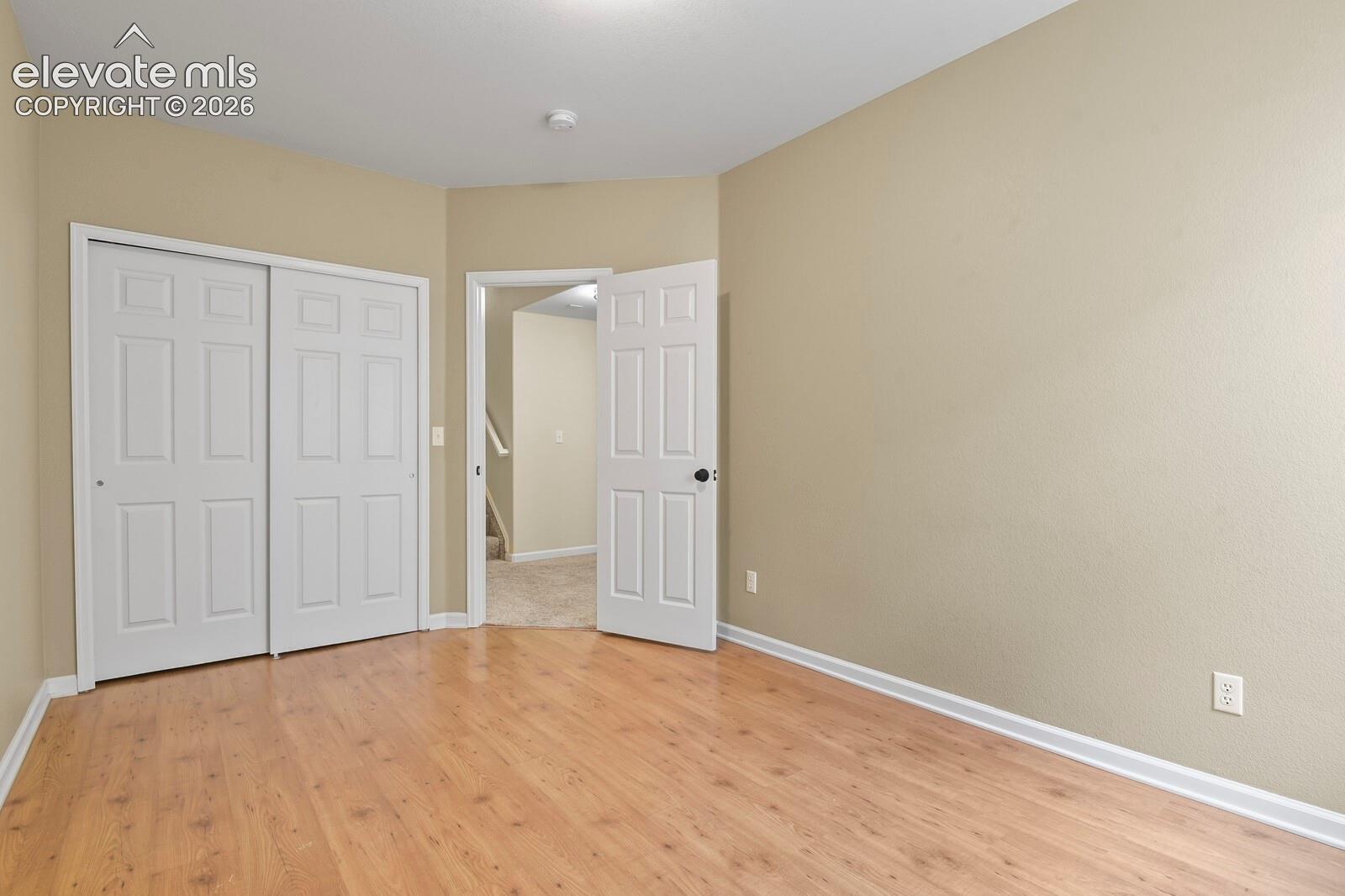 Room featuring wood-finish flooring, neutral wall paint, and white trim