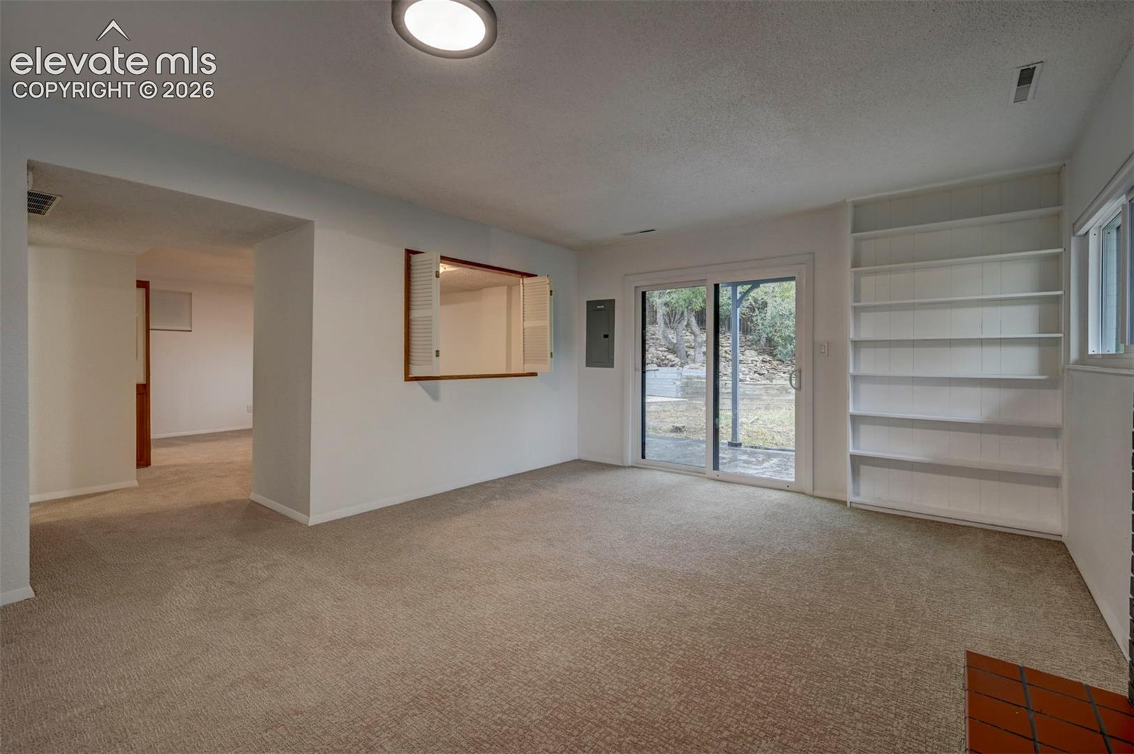 Built-in shelving, pass-through wall window with shutter doors, and sliding glass door with external patio access