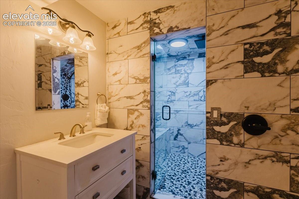 Walk-in shower with clear glass enclosure and stone pebble flooring