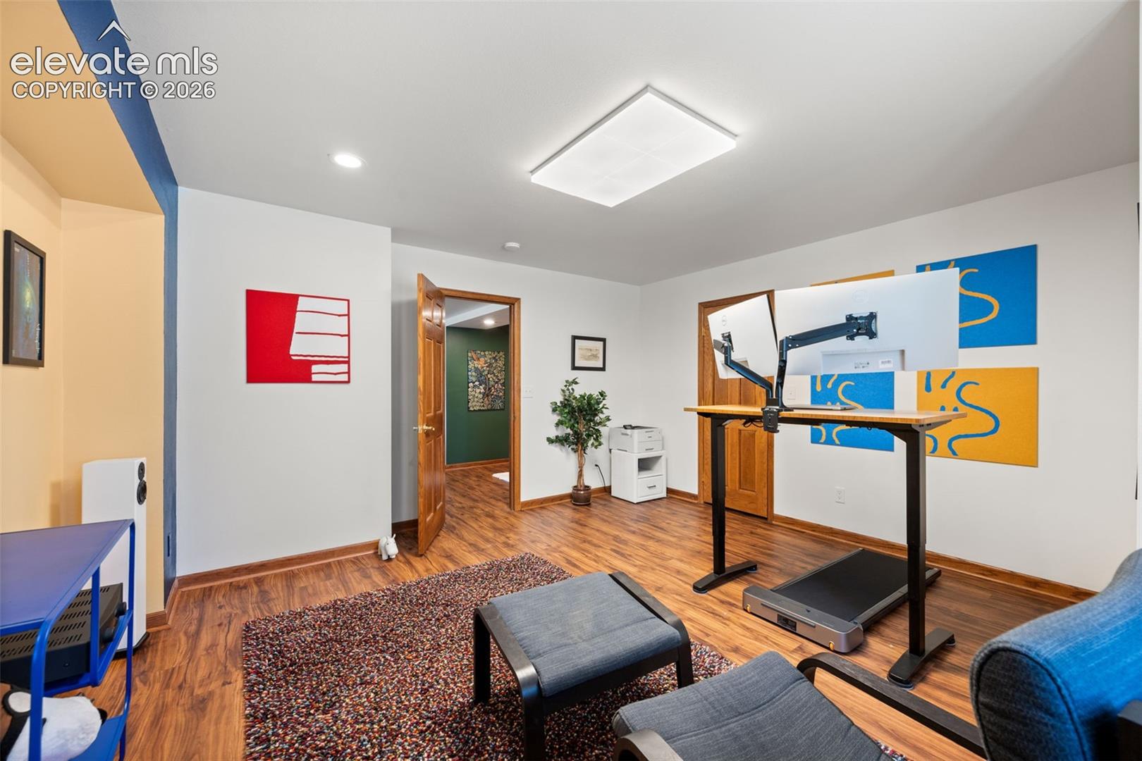 Interior room featuring wood-finish flooring, recessed lighting, a rectangular ceiling light fixture, and a wood-paneled door