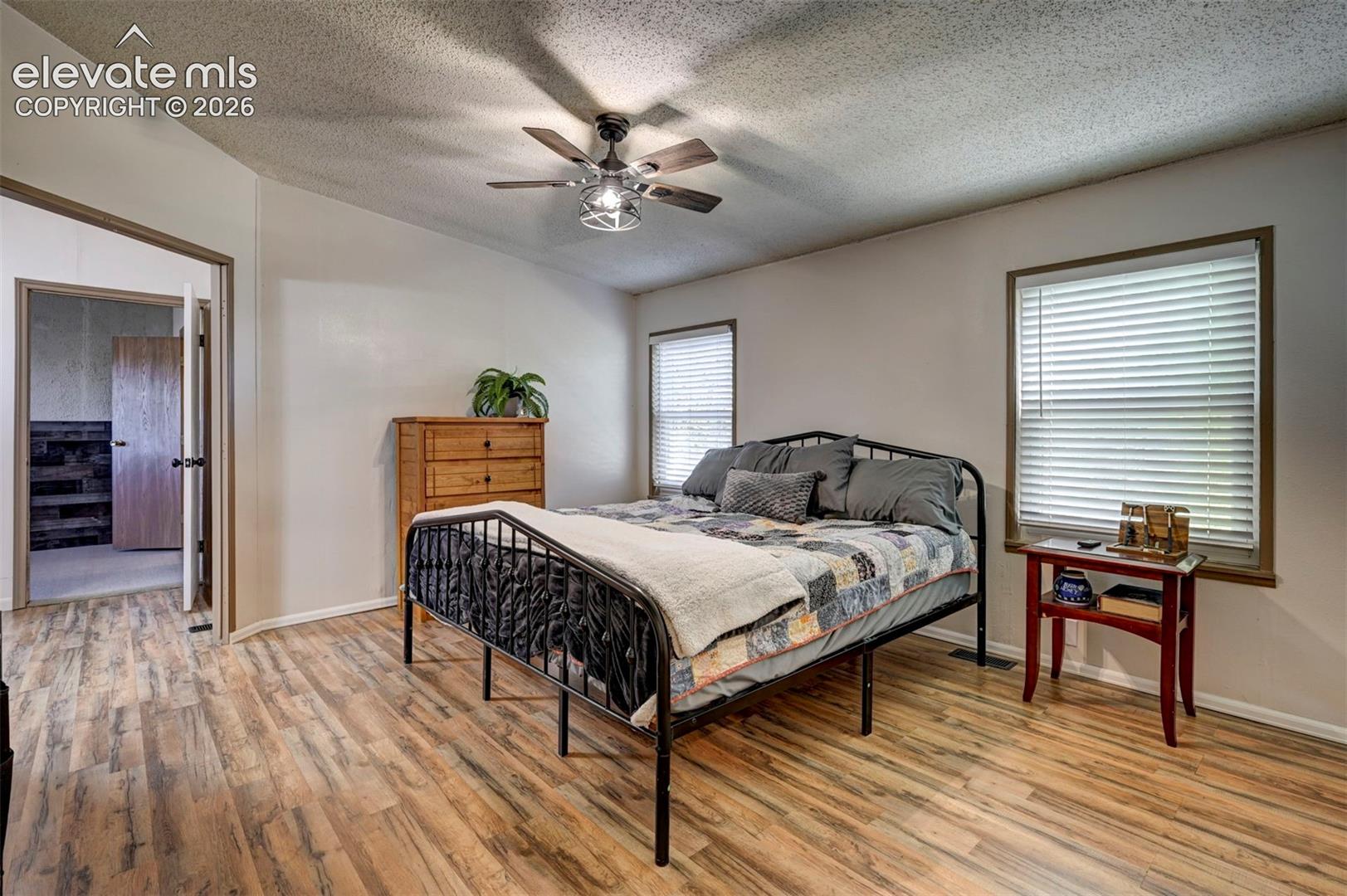 Bedroom with light wood-style flooring, a textured ceiling, and ceiling fan