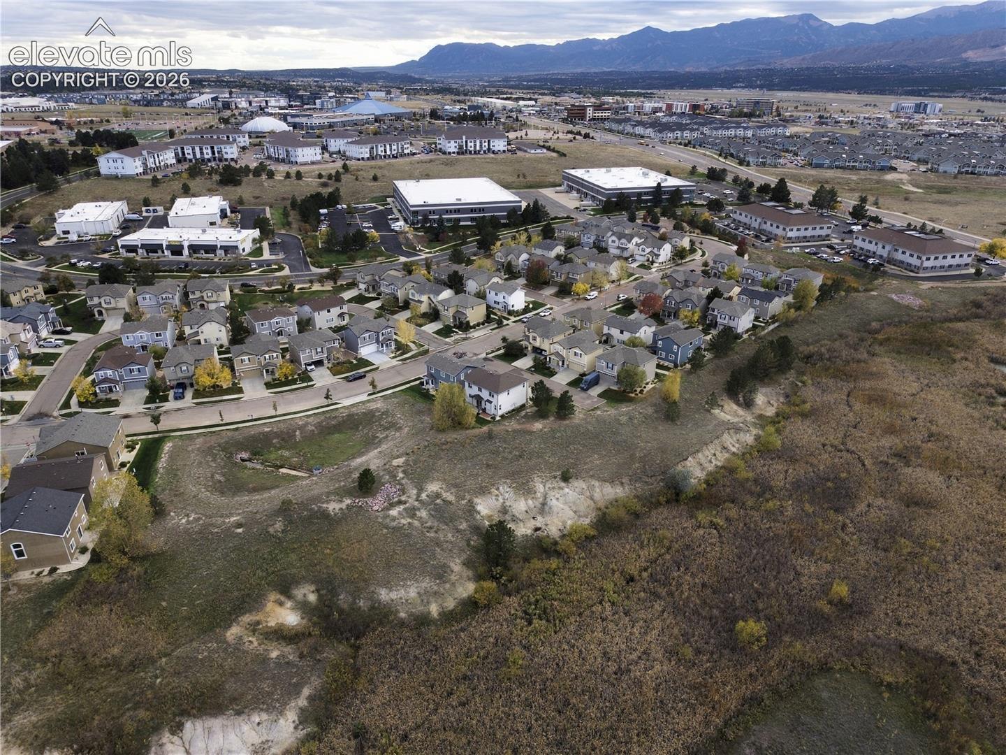 Aerial perspective featuring an expanse of natural terrain and residential development set against a mountain backdrop