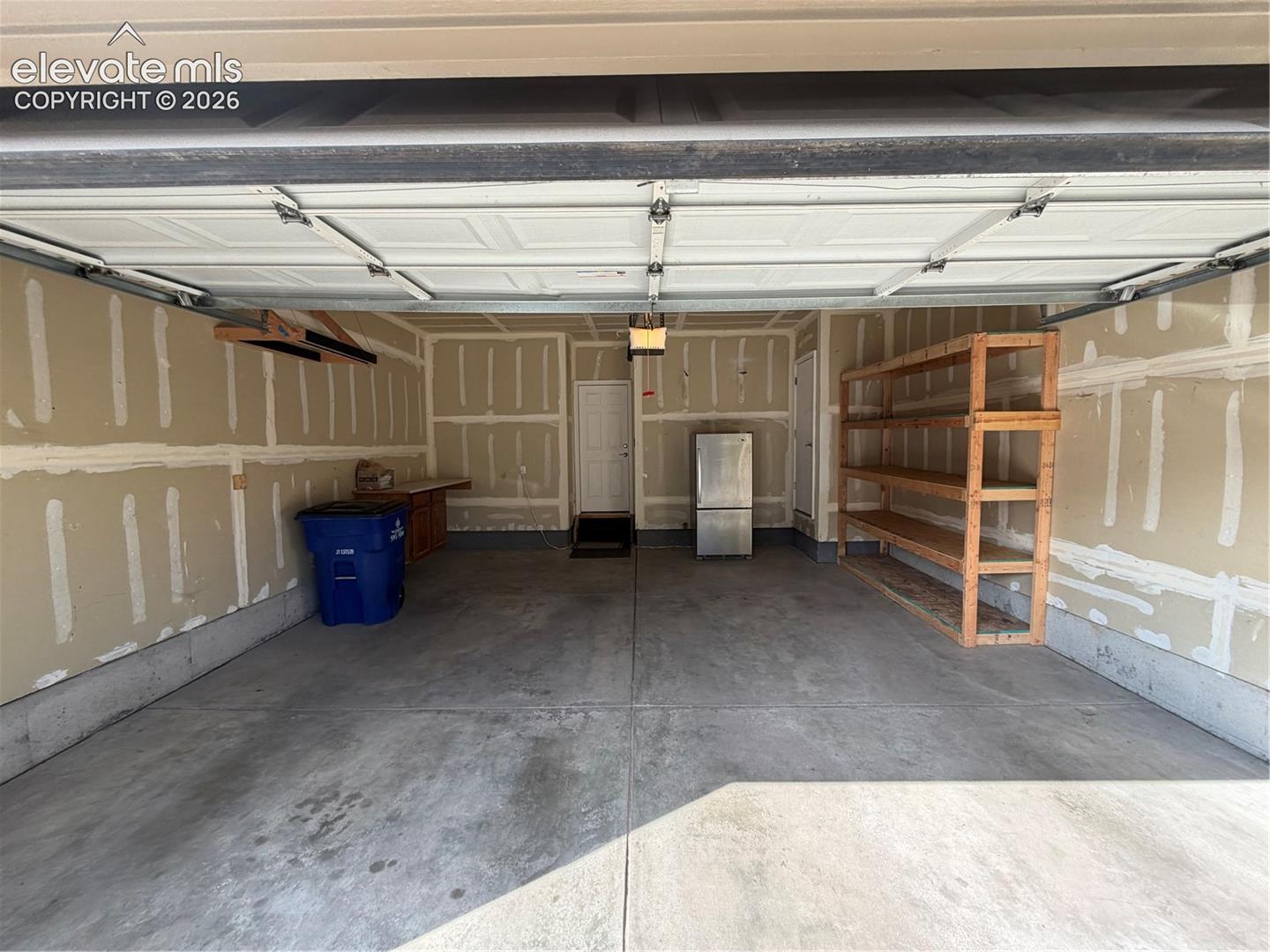 Concrete flooring, built-in shelving, overhead garage door, interior access door