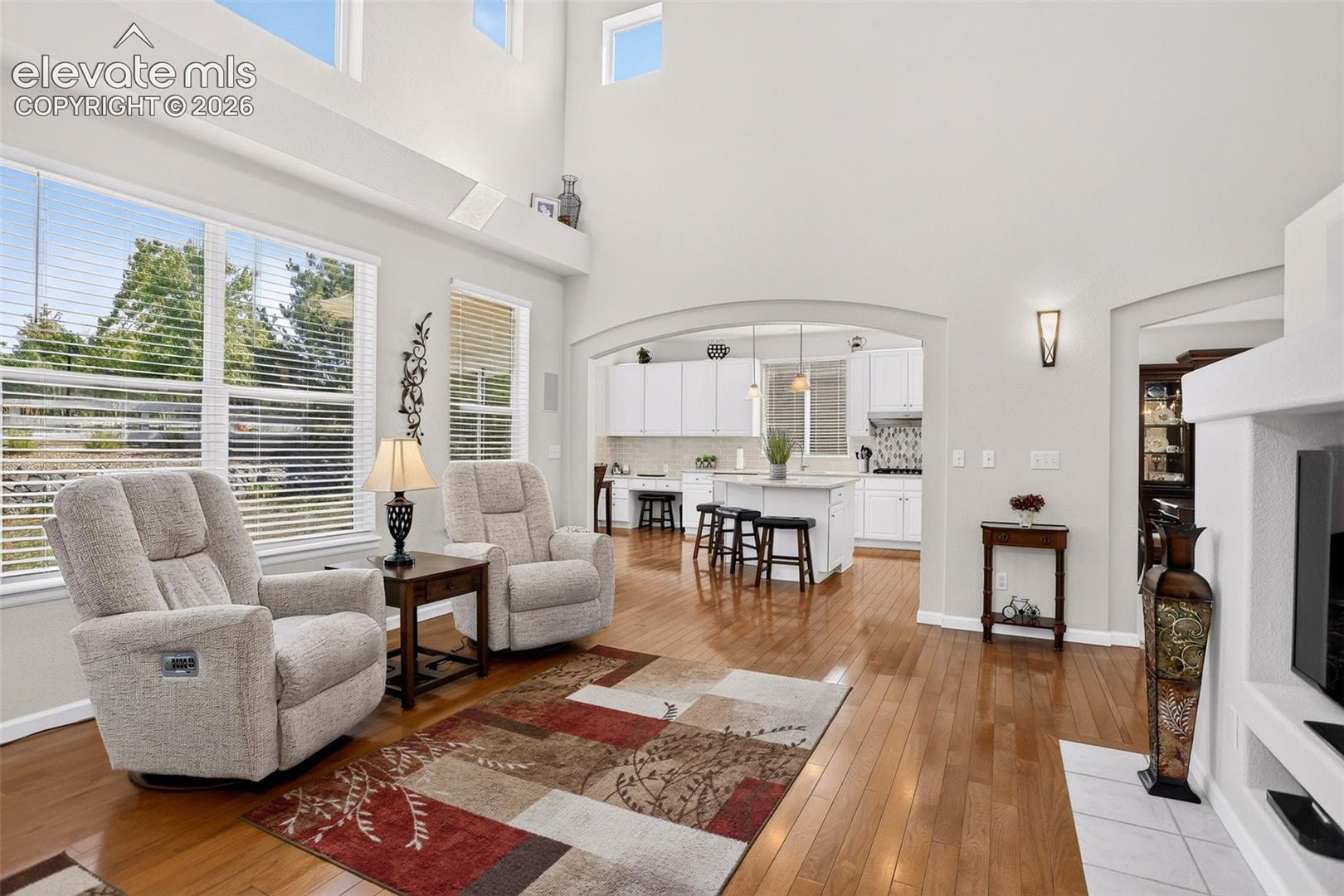 Hardwood flooring, arched doorways, high ceilings, large windows, and an open-concept design