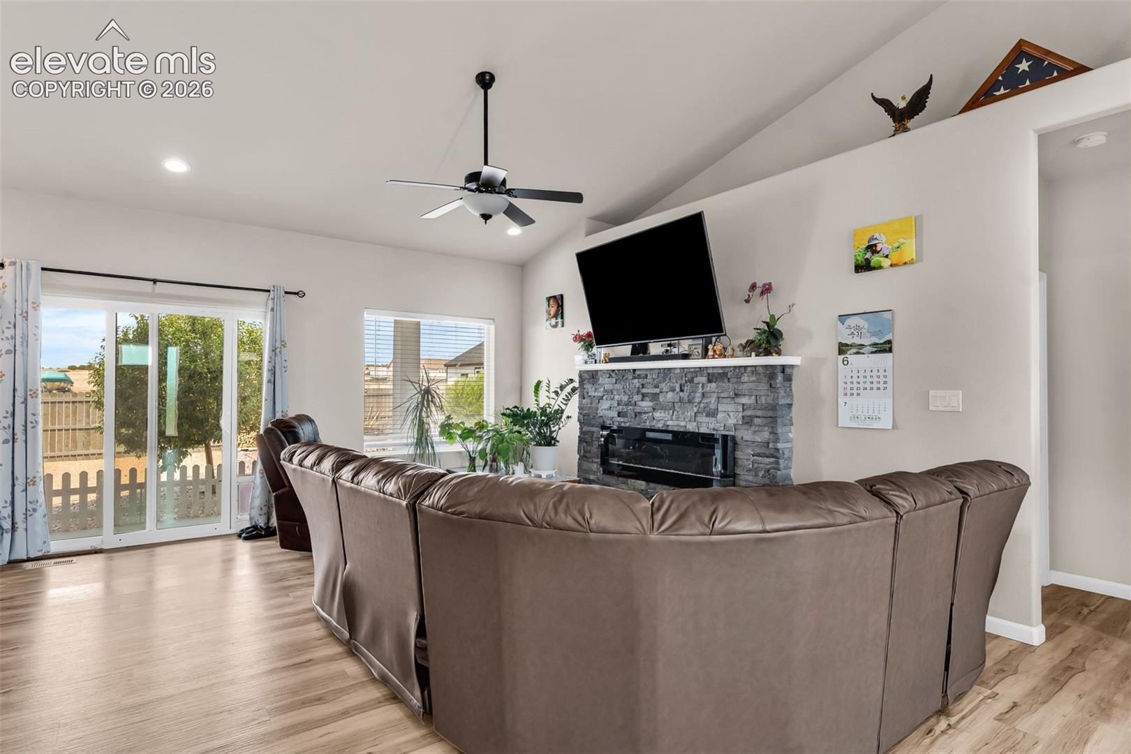 Living area featuring vaulted ceilings, recessed lighting, and wood-finish flooring
