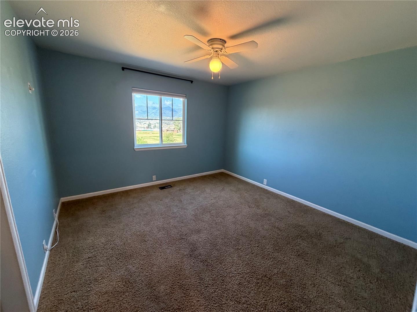 Ceiling fan with integrated lighting, carpeted flooring, window with white trim, and light blue wall finish