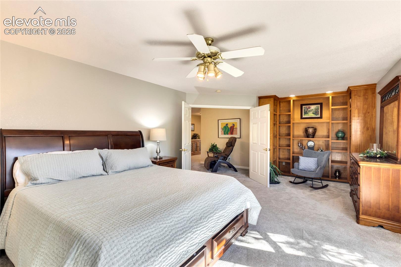 Built-in wood shelving unit, recessed lighting, white double doors, and ceiling fan with integrated light fixture