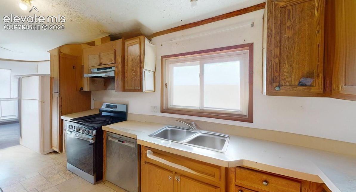 Kitchen featuring stainless steel appliances, light countertops, ventilation hood, and wood finish cabinetry