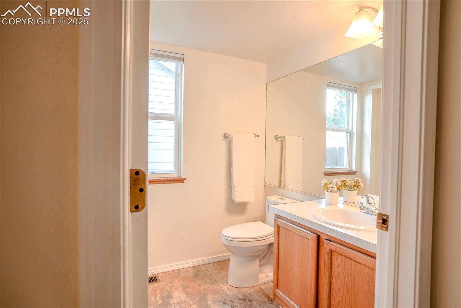 Half bathroom featuring vanity and toilet. Laundry area.