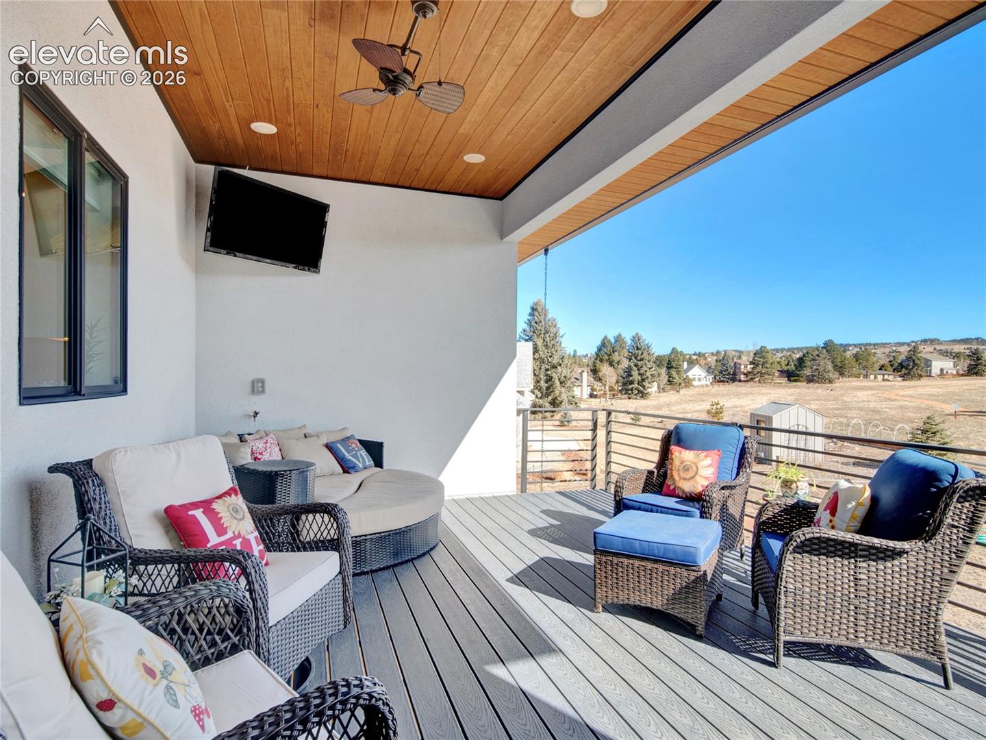 Covered outdoor living area featuring a wood-finish ceiling with recessed lighting and a ceiling fan, composite decking, and a metal cable railing system