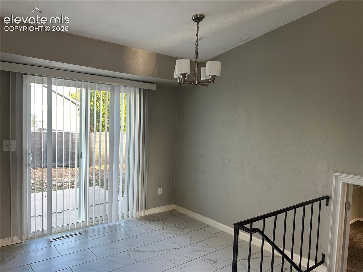 Tile flooring, sliding glass door with vertical blinds, and four-light metal chandelier