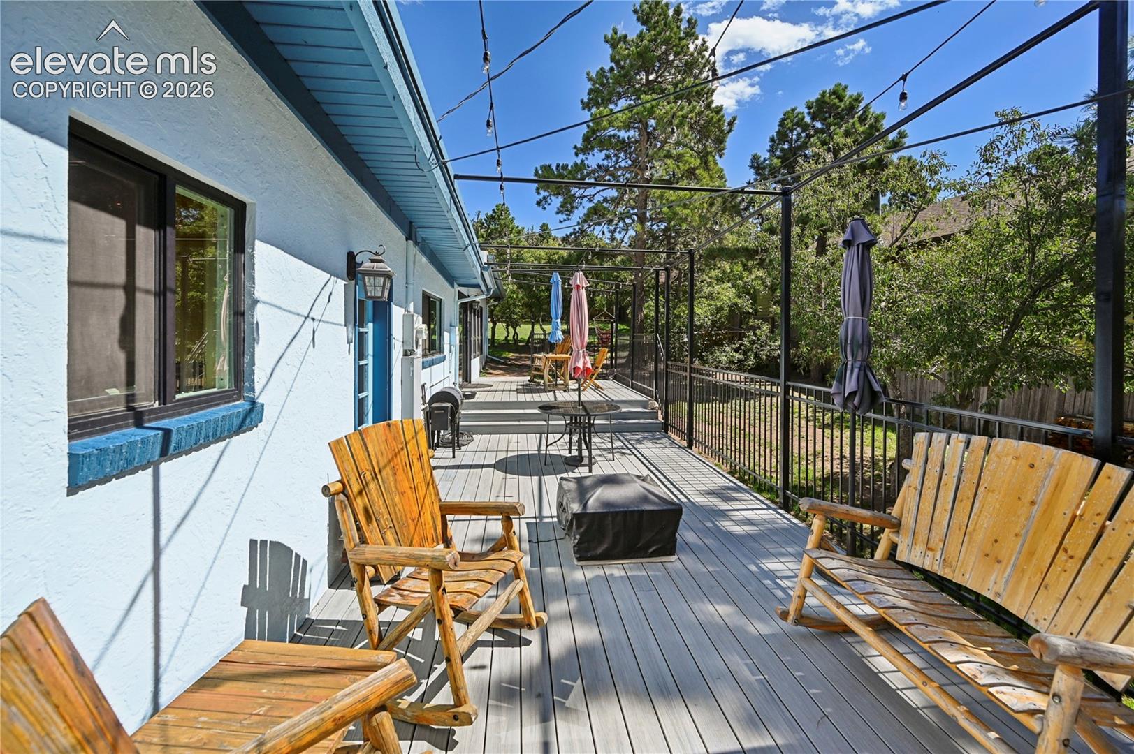 Expansive outdoor deck with gray composite decking, black metal railing, and a black pergola structure