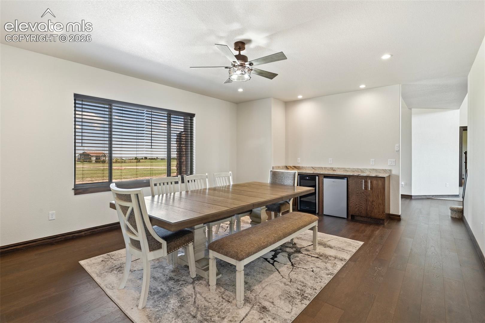 Spacious formal dinning room featuring wood-finish flooring, dry bar with wine fridge, recessed lighting, and a ceiling fan
