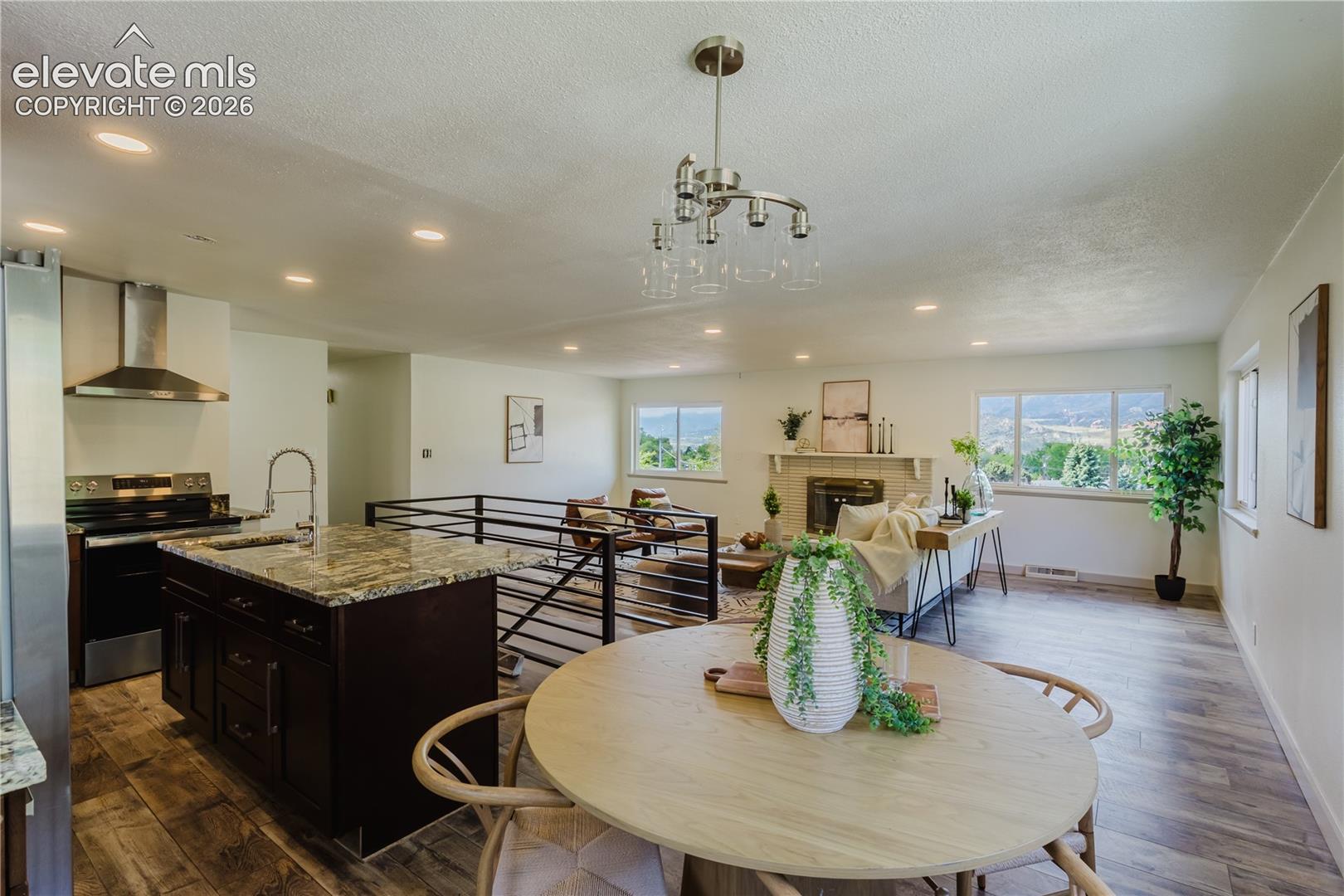 Open-concept living space featuring wood-finish flooring, recessed lighting, and a chandelier