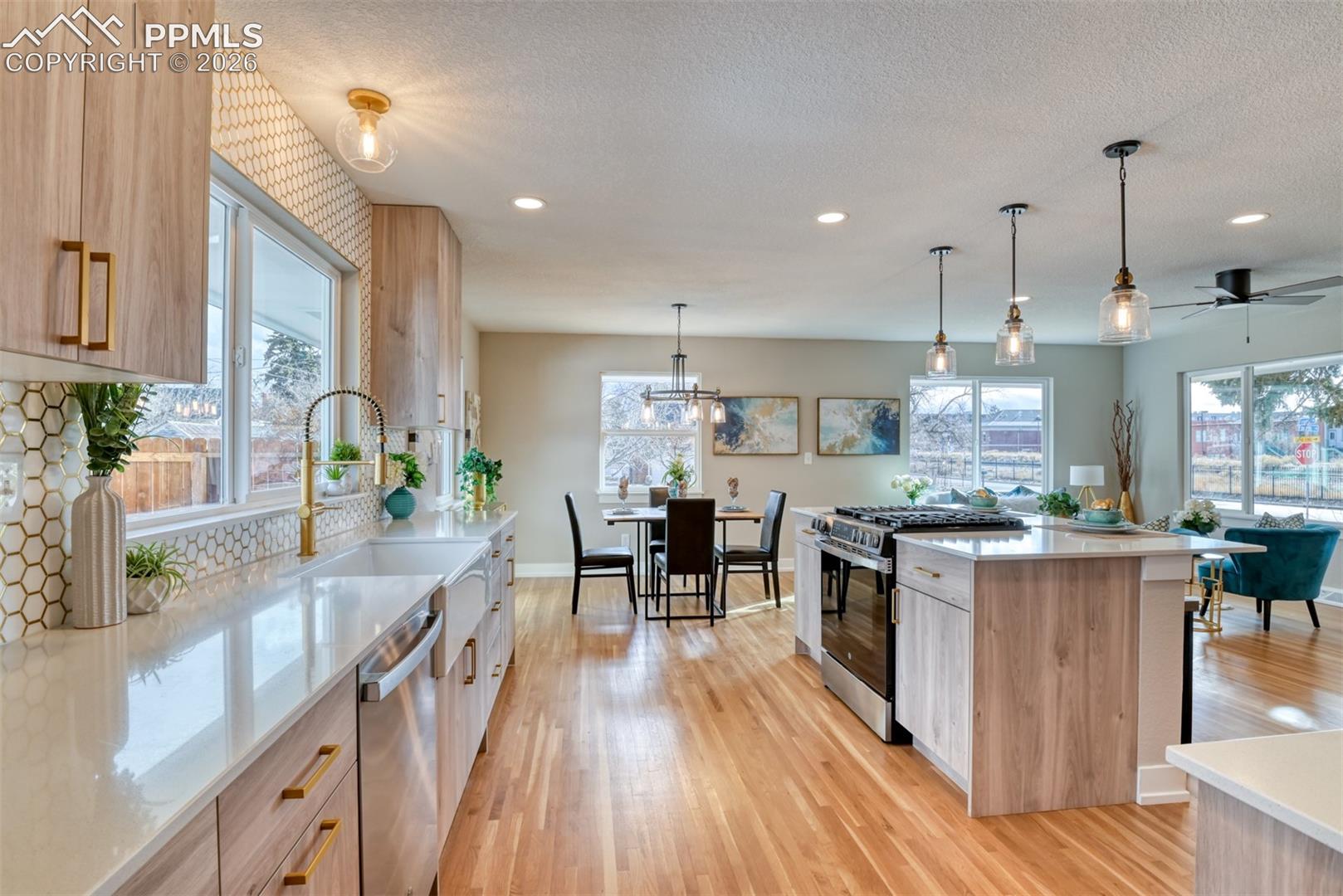 Kitchen with stainless steel appliances, pendant lighting, light wood-style flooring, a center island, and healthy amount of natural light