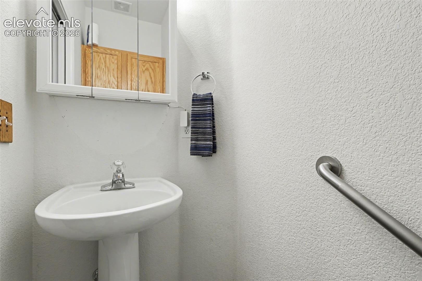 Main level half bath has toilet & pedestal sink