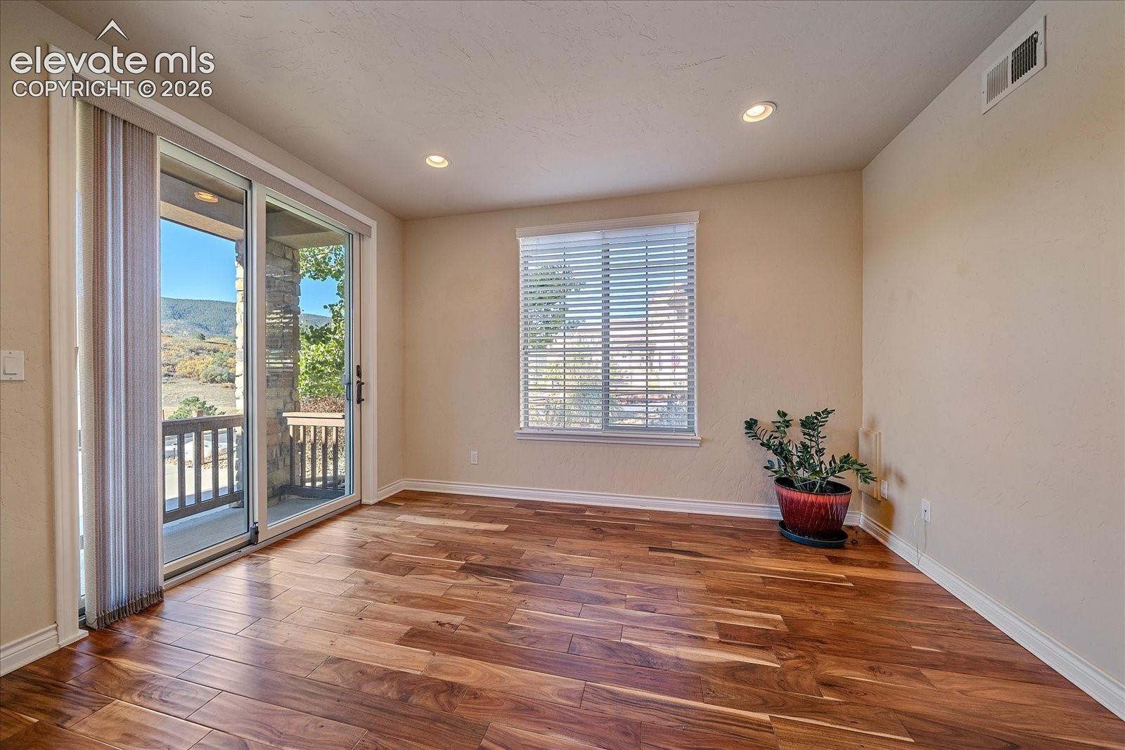 Wood-finish flooring, recessed lighting, sliding glass door, and large window with horizontal blinds