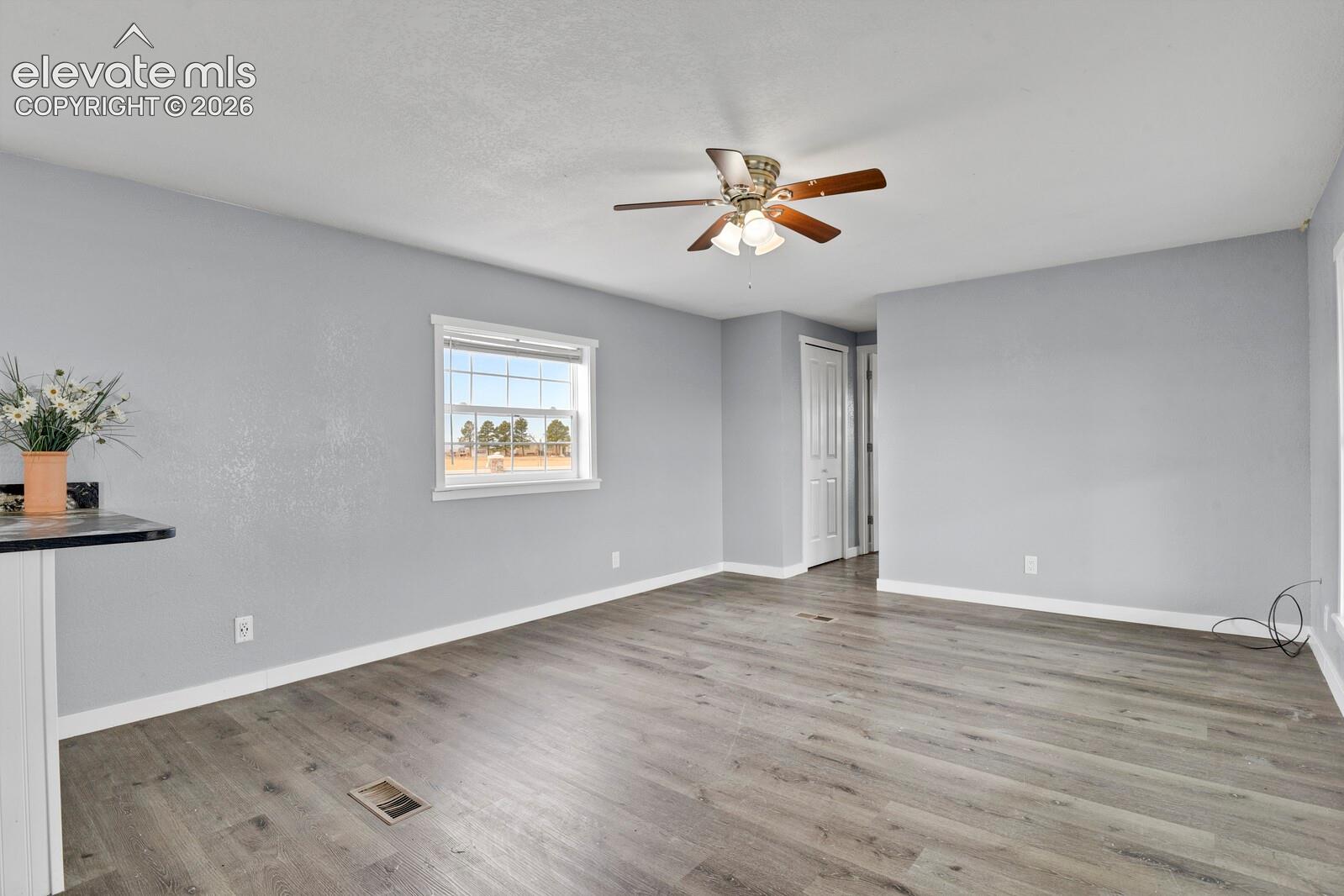 Interior space featuring wood-finish flooring, a multi-light ceiling fan, a window with muntins, and a closet with a paneled door