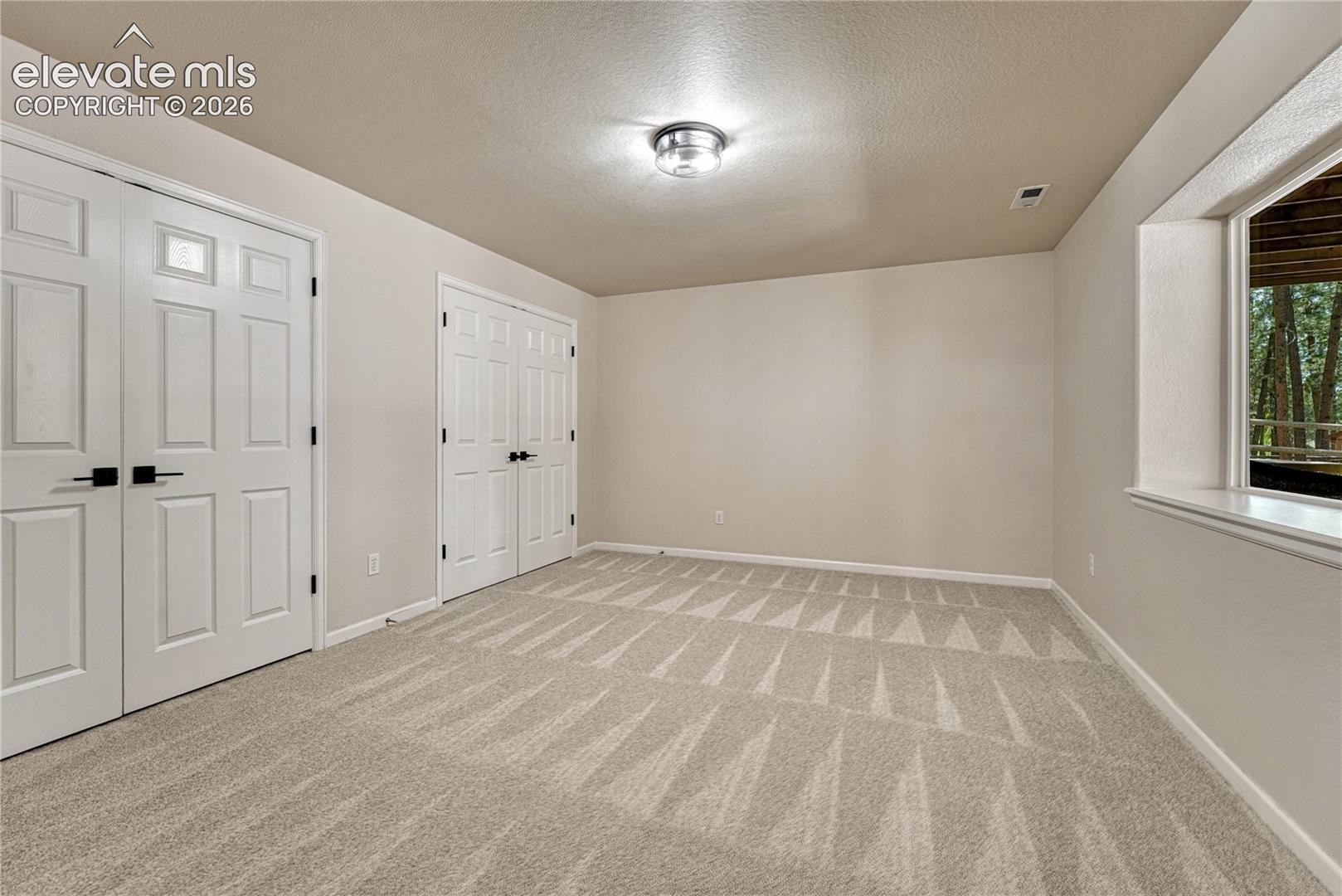 Large basement bedroom with above-grade window and two closets. 