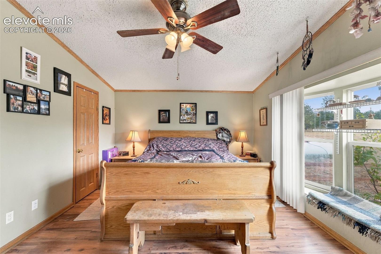 Wood-finish flooring, ceiling fan with integrated lighting, wood trim detailing, and a large multi-pane window featuring a built-in sill