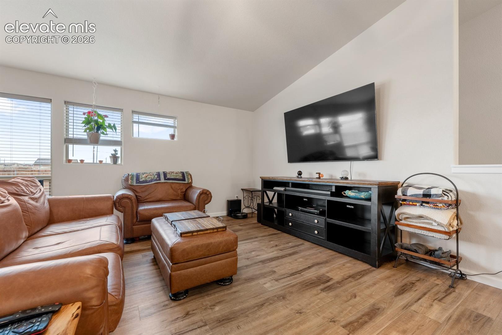 Living area featuring wood-finish flooring, vaulted ceilings, and multi-paned windows