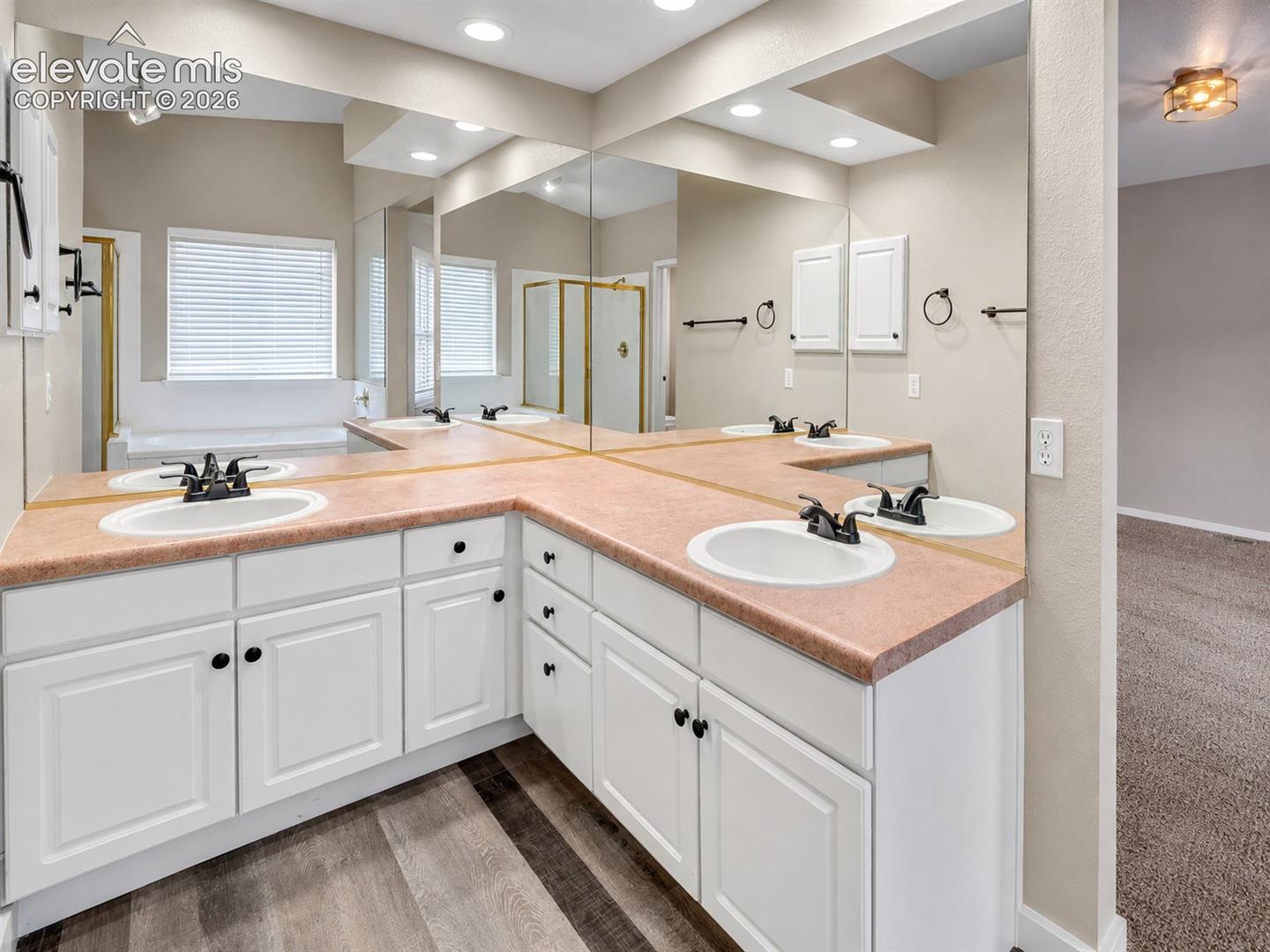 Bathroom featuring a dual vanity with white cabinetry, integrated sinks, and a large wall-mounted mirror