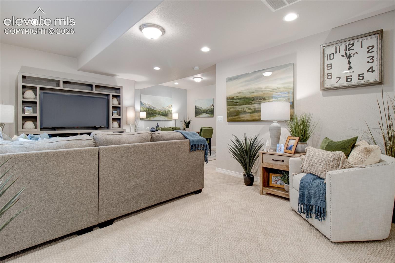 Neutral-toned living space featuring wall-to-wall carpeting, recessed ceiling lighting, and custom built-in cabinetry