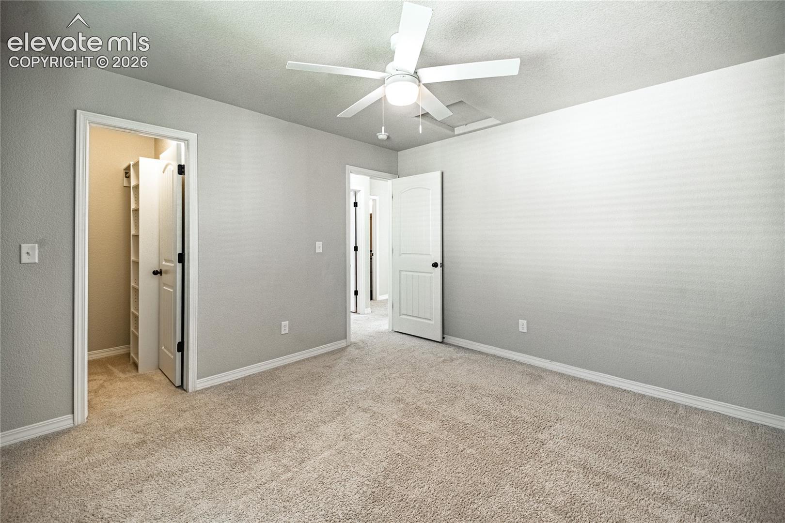 Plush carpeting, a ceiling fan with integrated lighting, and a closet with built-in shelving