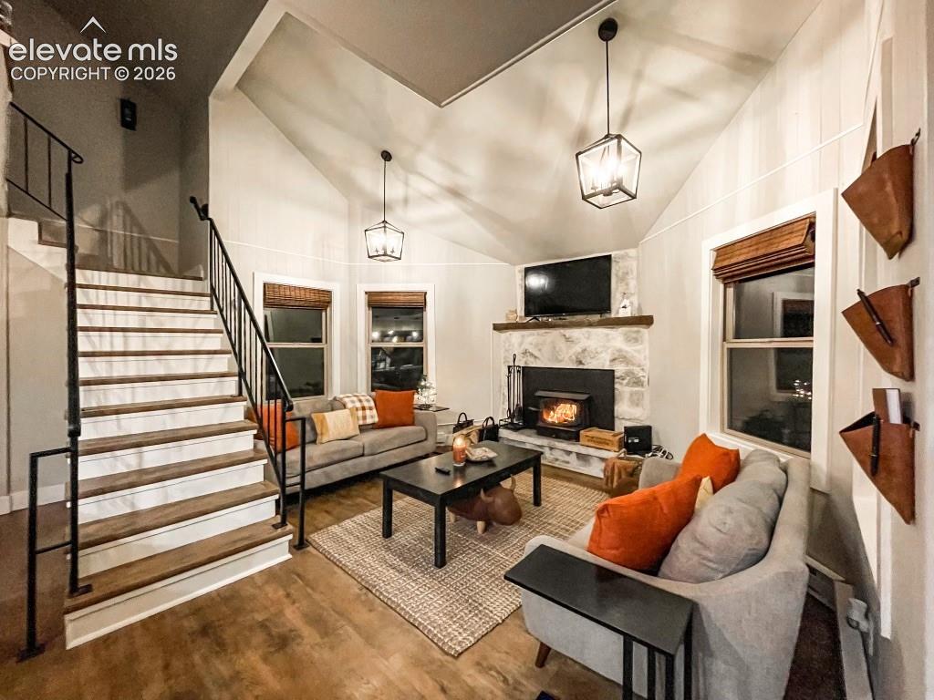 Vaulted ceiling living area featuring wood-finish flooring and a stone-clad fireplace