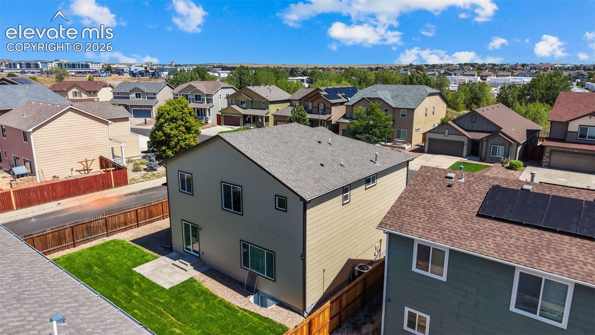 Two-story residence with a pitched roof, exterior siding, and a fenced backyard featuring a grassy area and concrete patio