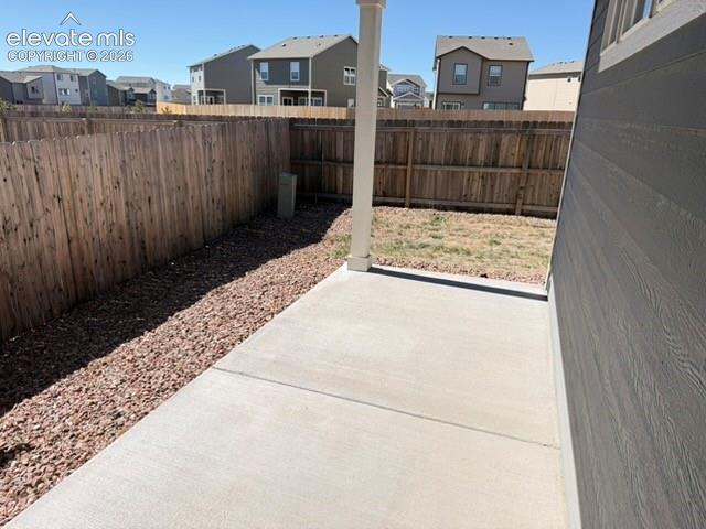 Concrete patio with a wood privacy fence, gravel landscaping, and siding exterior
