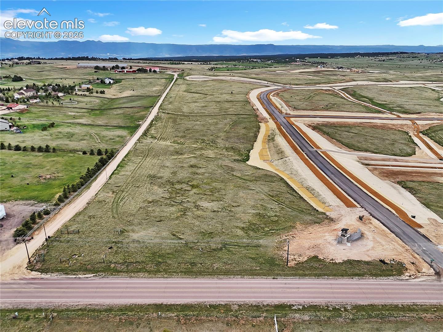 Expansive undeveloped acreage featuring paved street access, utility connection points, and mountain range scenery