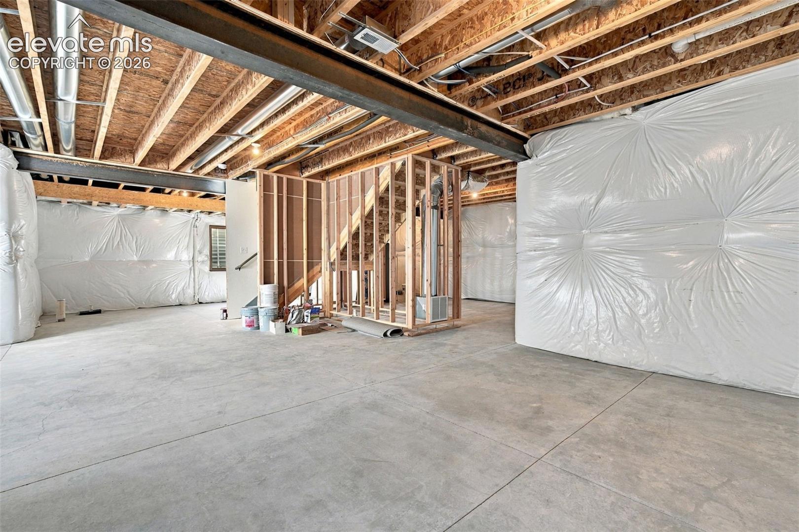 Unfinished basement with exposed ceiling joists, and concrete flooring