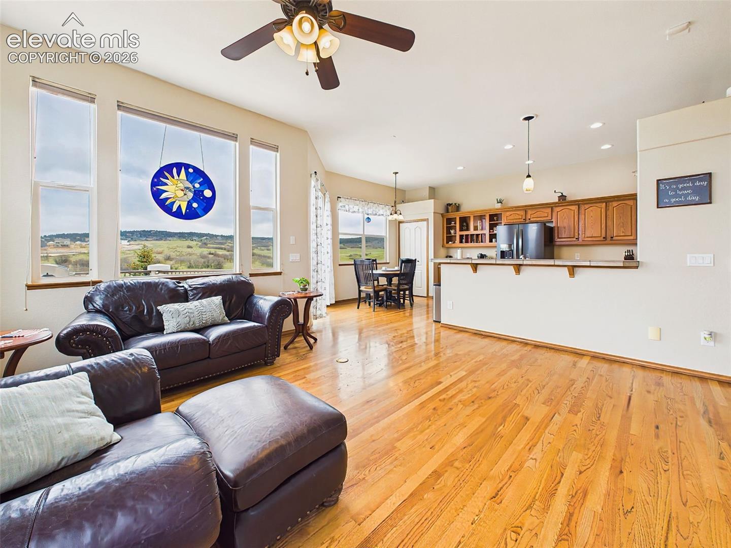Open-concept great room with soaring ceilings, hardwood floors, and large picture windows showcasing the surrounding views.