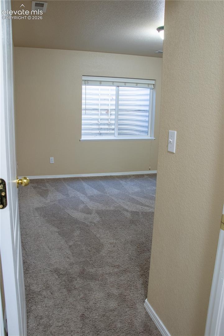 Carpeted room with a single window featuring horizontal blinds