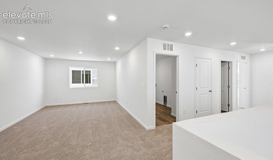 Neutral-toned carpet, recessed lighting, white interior doors, and a sliding window