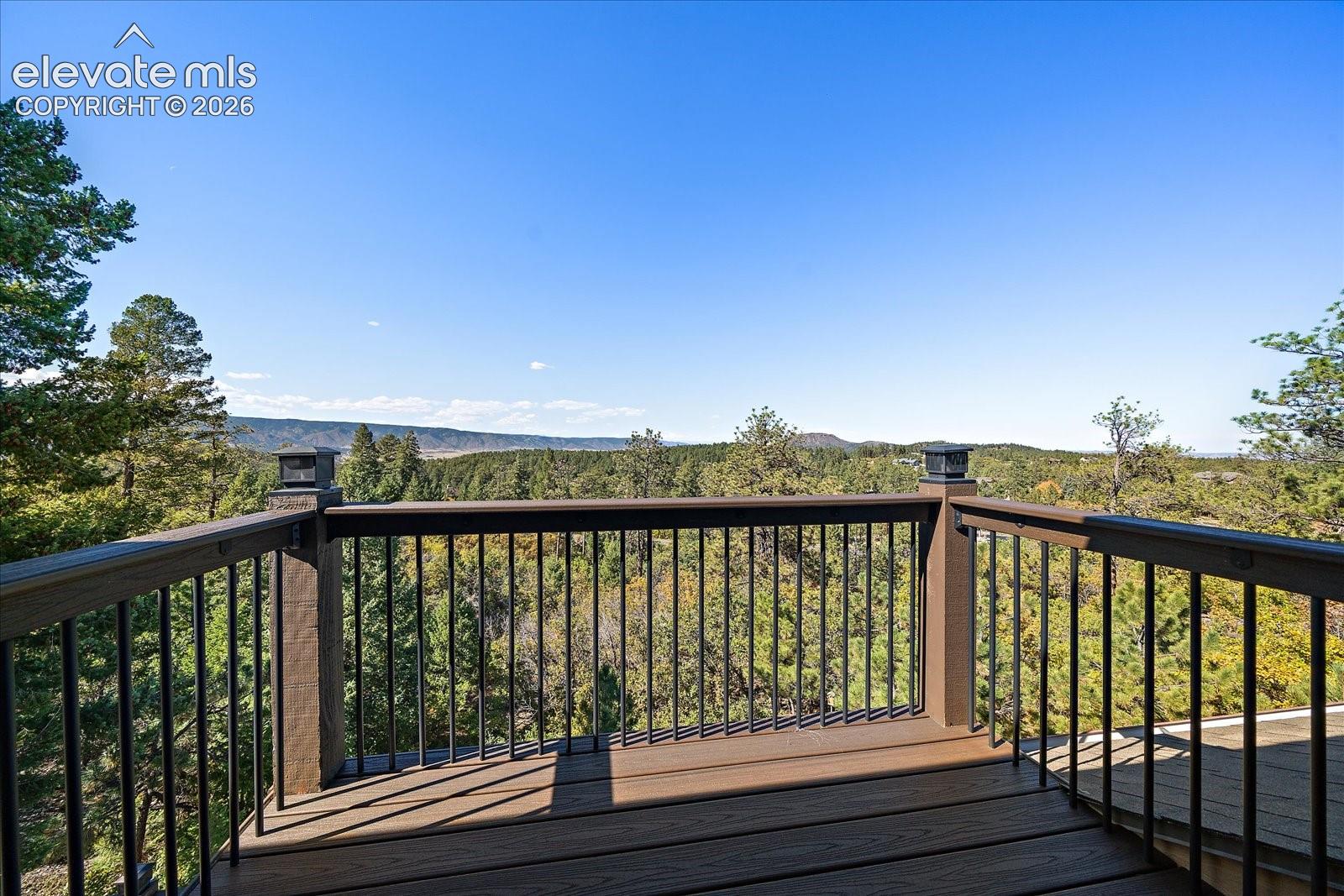 Elevated deck featuring composite decking, dark metal railings, and built-in post cap lighting