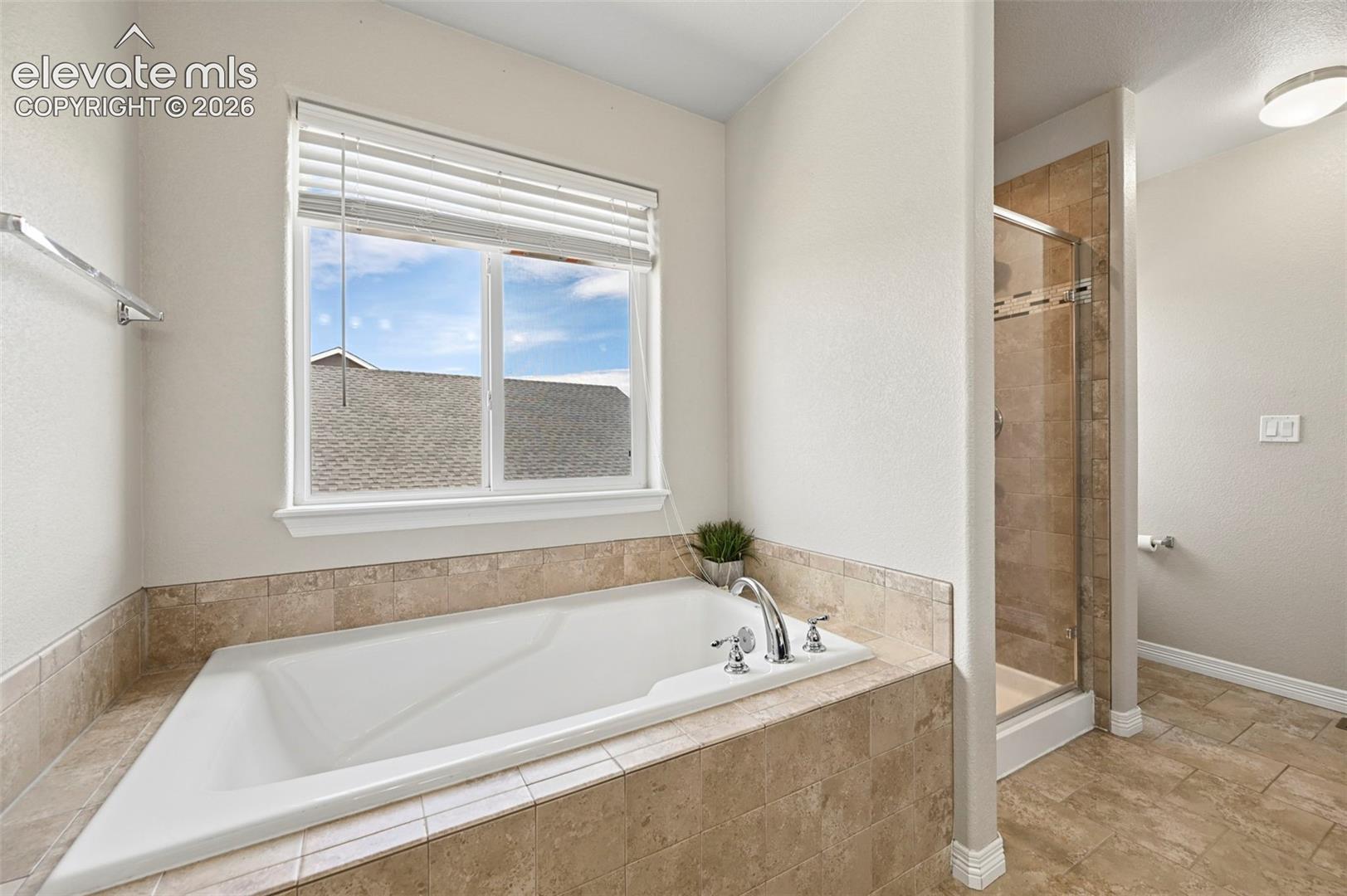 Built-in soaking tub with polished chrome fixtures, surrounded by neutral-toned tile
