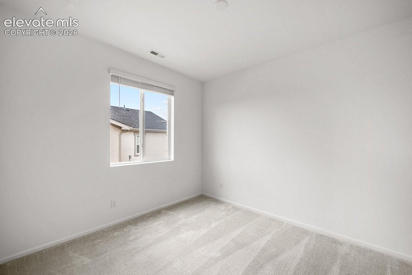Light-toned wall-to-wall carpeting, white painted walls, and a single window with blinds