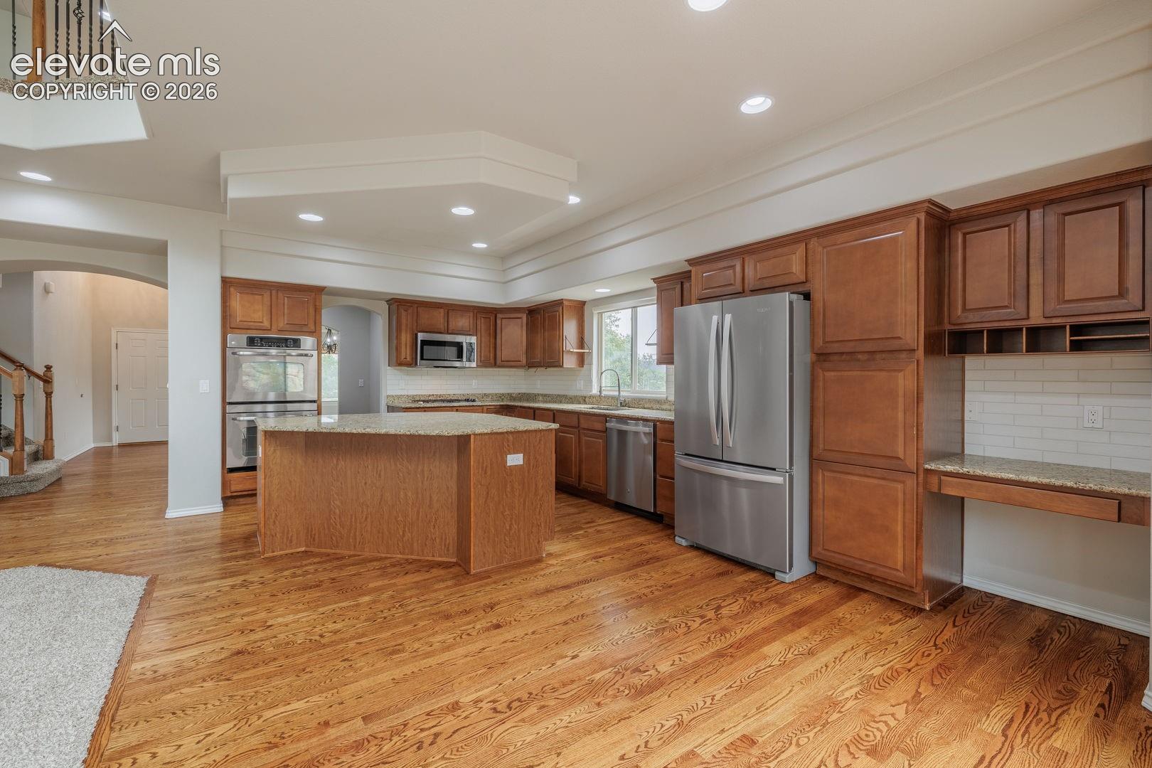 Spacious kitchen featuring wood-finish flooring, recessed lighting, and rich wood cabinetry