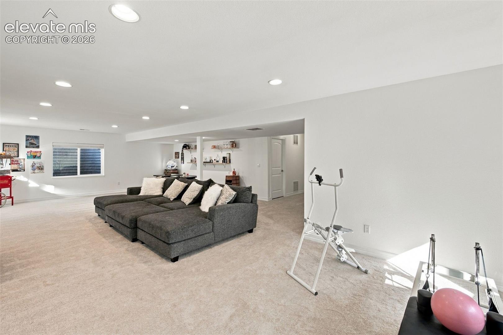 Expansive interior space featuring neutral wall-to-wall carpeting, recessed ceiling lighting, and built-in shelving