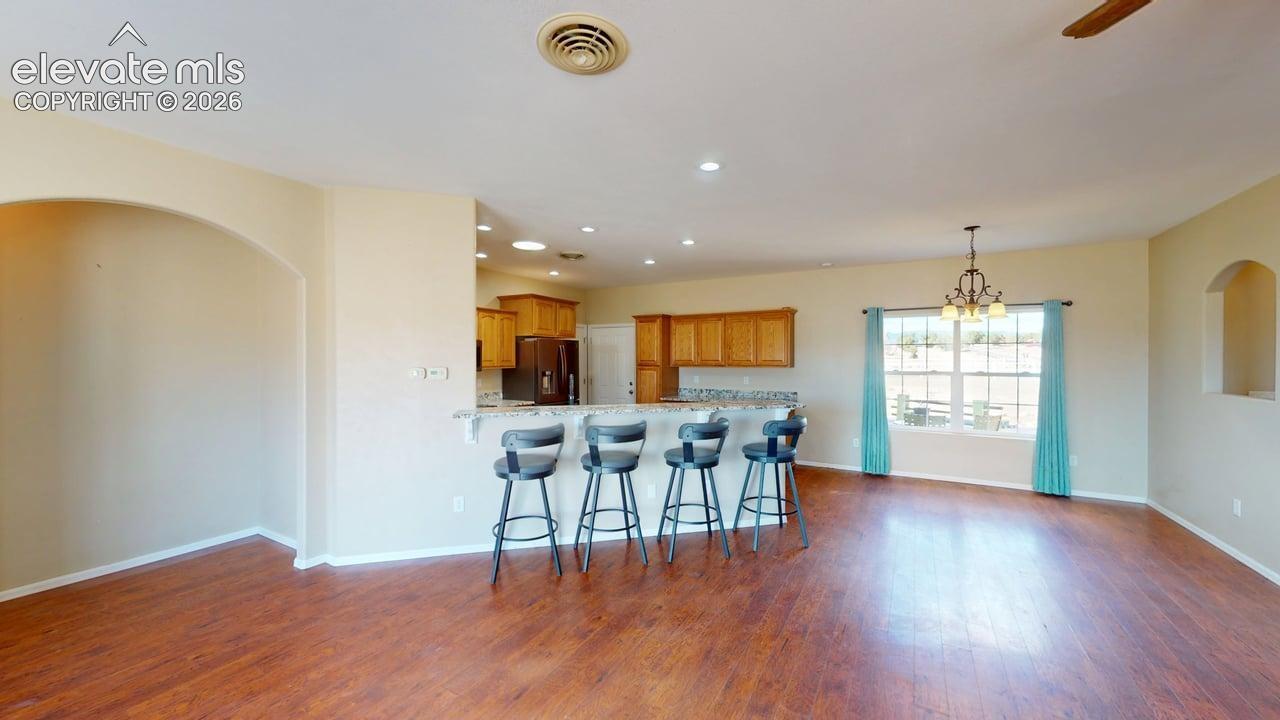 Wood-finish flooring throughout, arched wall opening, recessed lighting, and a breakfast bar with built-in cabinetry