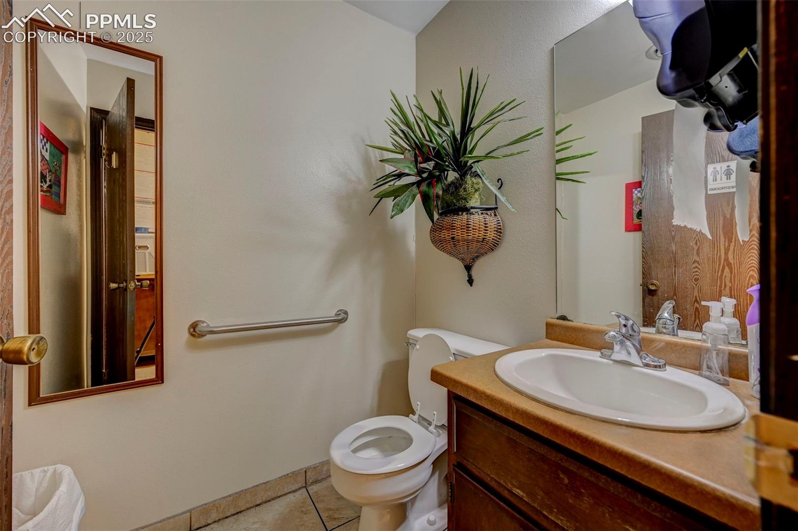 Bathroom with toilet, tile patterned floors, and vanity