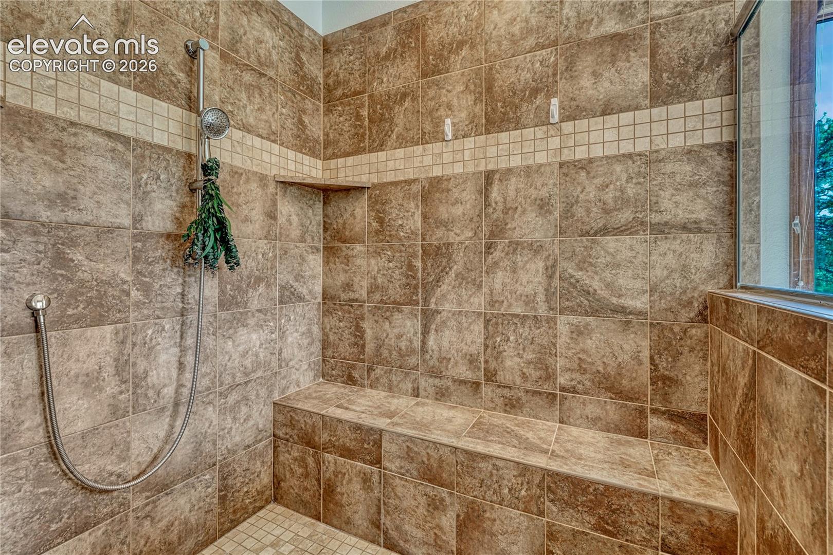 Oversized tile shower with bench seat and a mud set tiled shower pan.