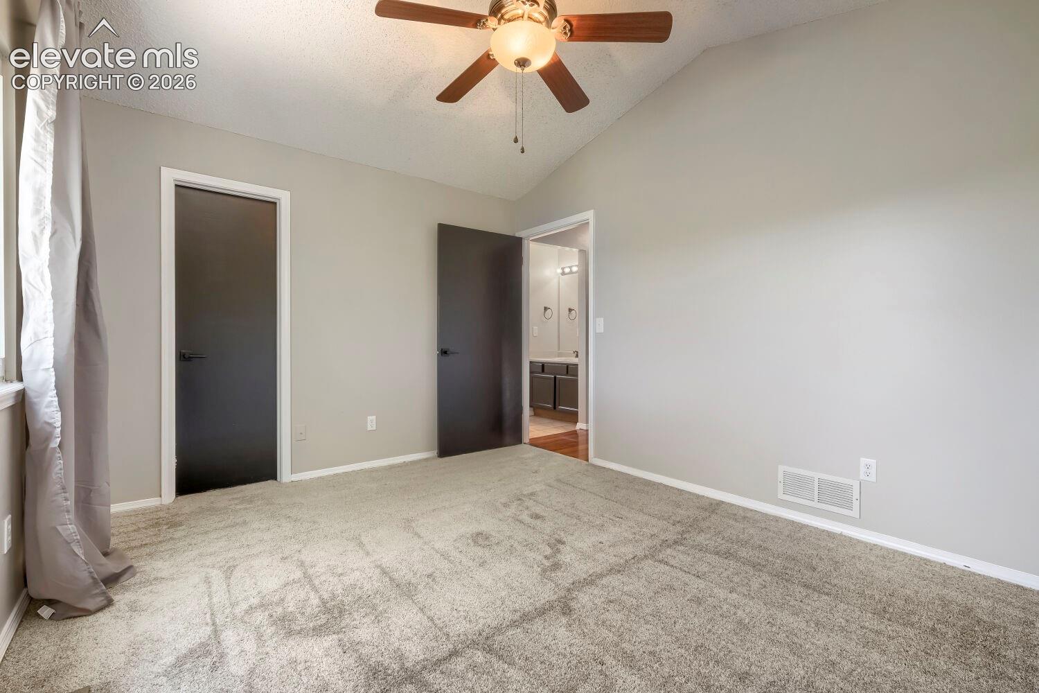 Vaulted ceiling room with ceiling fan light fixture, gray carpet flooring, and neutral wall paint