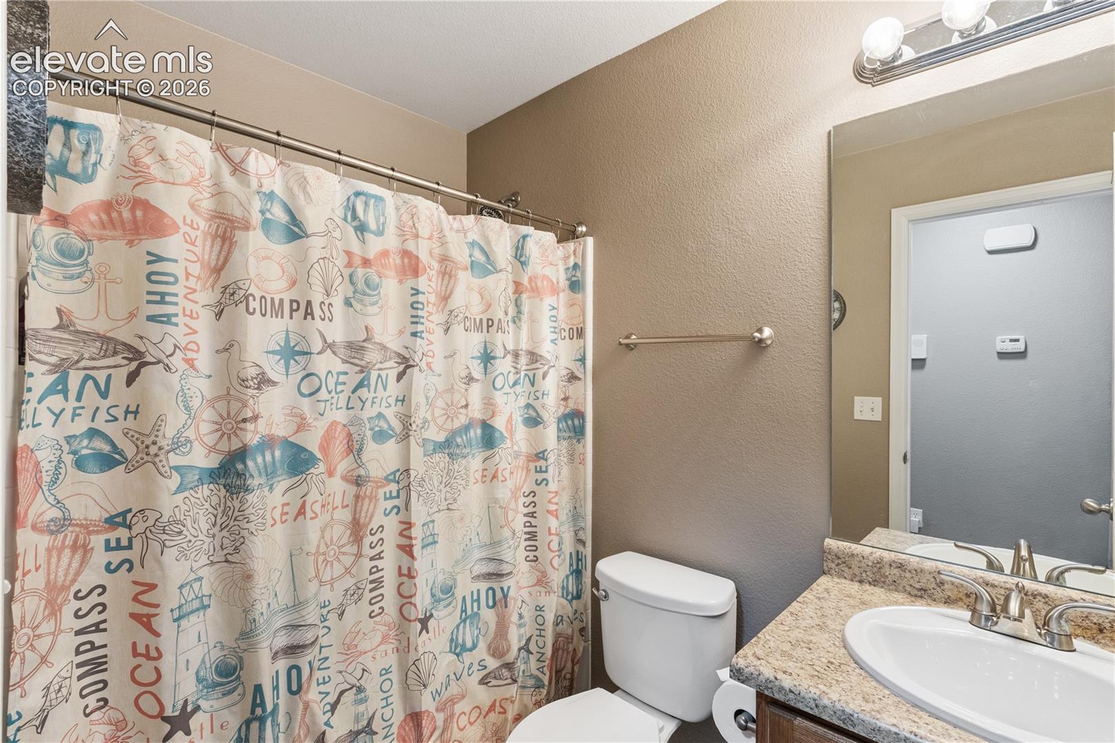 Bathroom featuring a vanity with a stone-composite countertop, an integrated oval basin, a wall-mounted mirror, and a multi-bulb light fixture