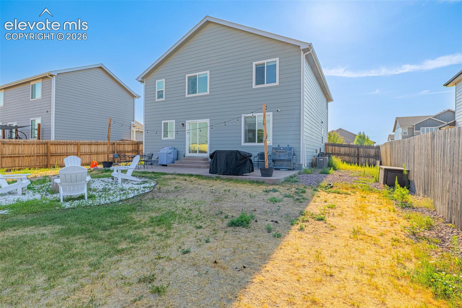 Spacious backyard featuring a concrete patio, sliding glass door access to the interior, and a fenced perimeter